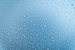 Wassertropfen haften an einer Glasscheibe. Dieses Bild steht symbolisch für die das Entkalken.